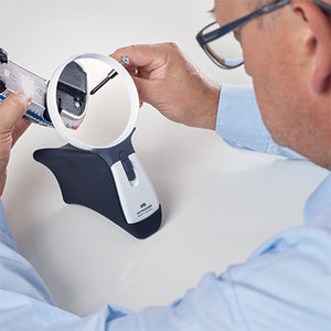 man using magnifier in stand to work on hobby